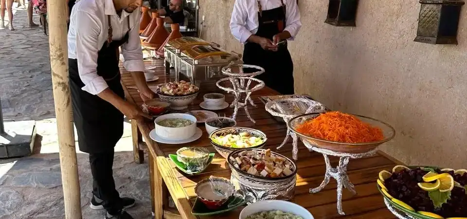Moroccan cuisine served at Marrakech Stay Vip, featuring traditional dishes presented at an outdoor setting with Moroccan lanterns and cultural decor, perfect for a memorable dining experience in Marrakech.