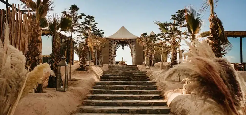 Luxurious Marrakech Stay Vip resort entrance with desert-themed architecture, palm trees, and scenic steps perfect for a relaxing Moroccan vacation.