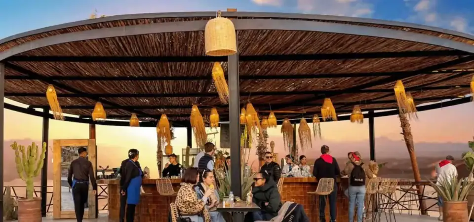 Stylish rooftop bar in Marrakech with sunset views, outdoor seating, and Moroccan-inspired decor, perfect for relaxing and enjoying drinks in a vibrant, luxurious setting.