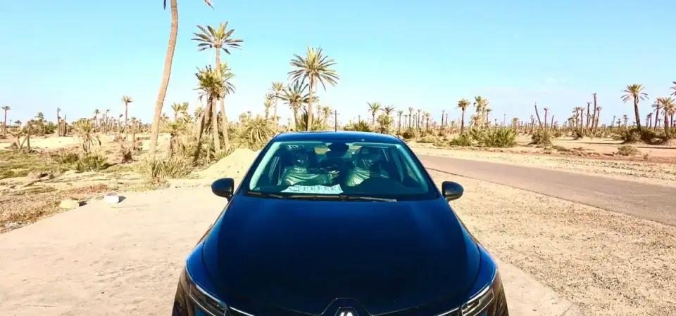 Renault car parked on a desert road with palm trees under clear blue sky in Marrakech.